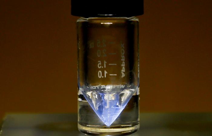 A purified sample of actinium-225, produced at ORNL’s Radiochemical Engineering Development Center, glows blue when the air that surrounds it is ionized by alpha particles. The FDA has acknowledged receipt of the Drug Master File for Ac-225 nitrate, an in-demand ingredient in targeted cancer treatments. Credit: ORNL, U.S. Dept. of Energy