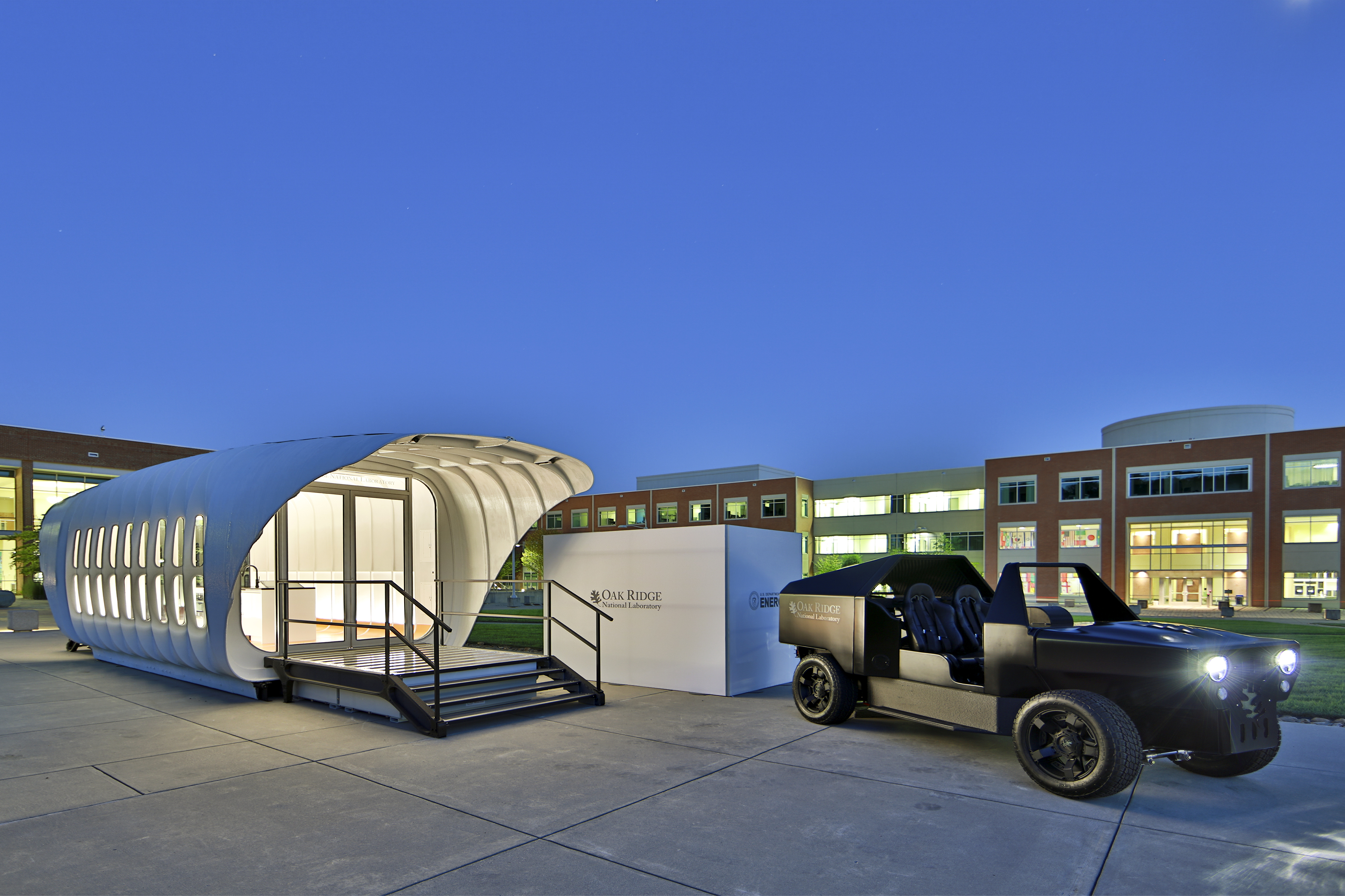 3d printed house and SUV photographed at night with lights glowing at night