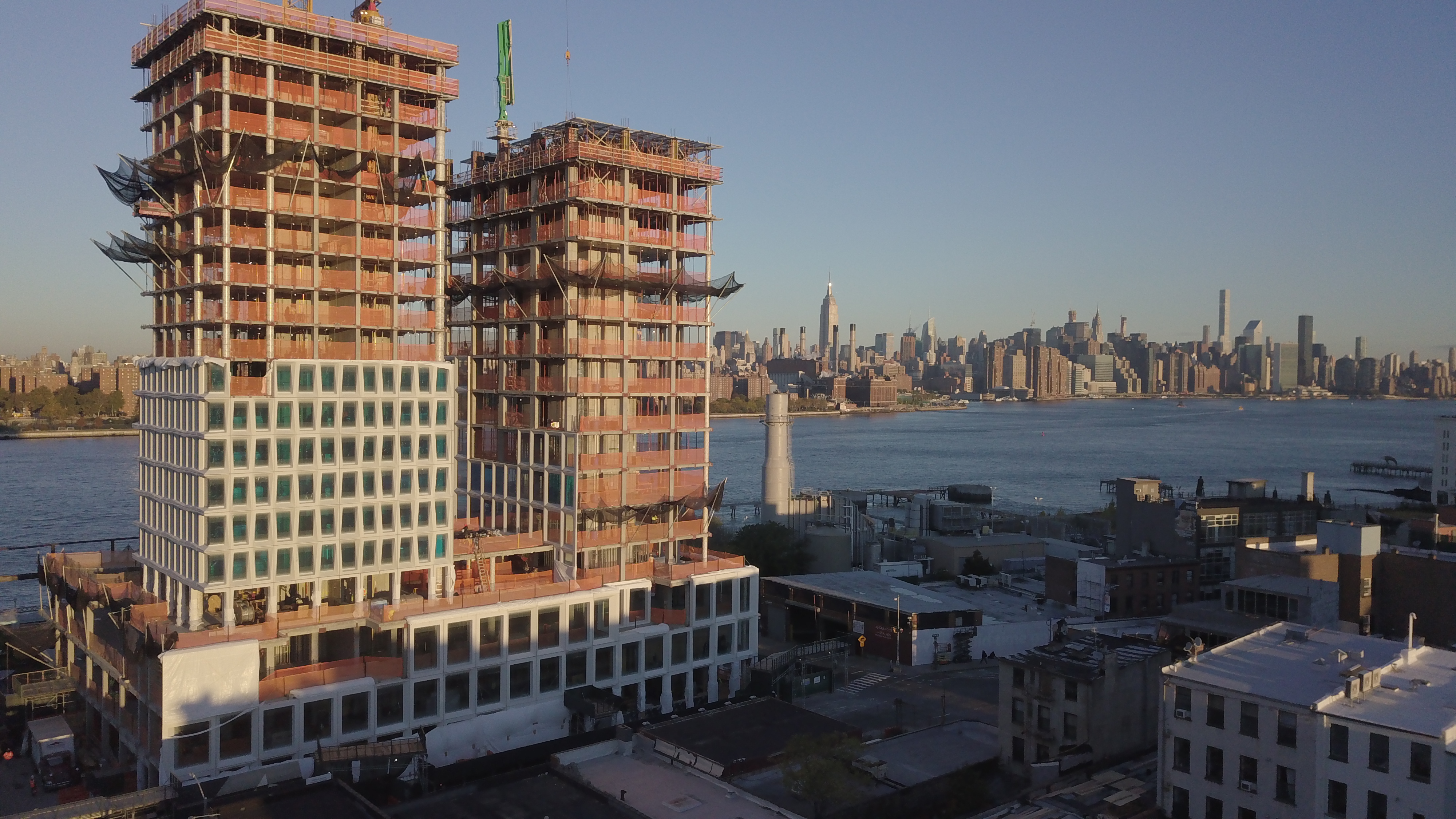 Birds eye view of the Domino Sugar building under construction, bottom half of the building has concrete facade and upper portion is open with scaffolding.