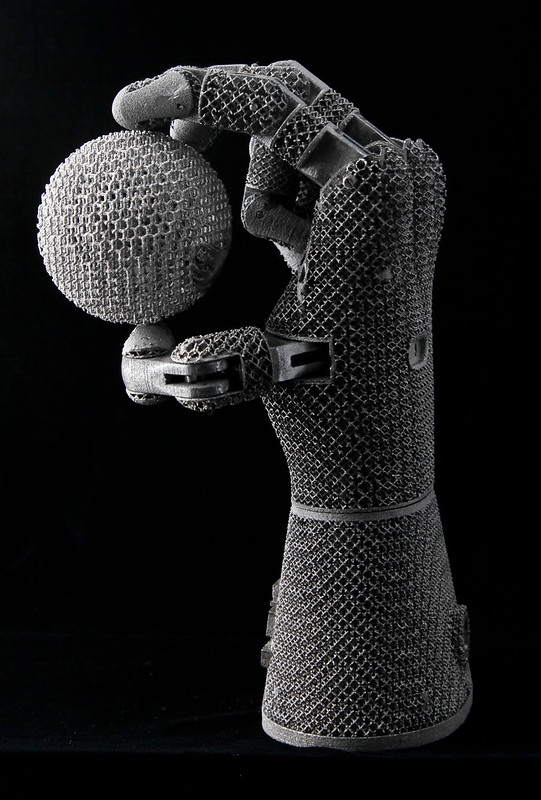 Titanium 3d printed hand holding a mesh sphere