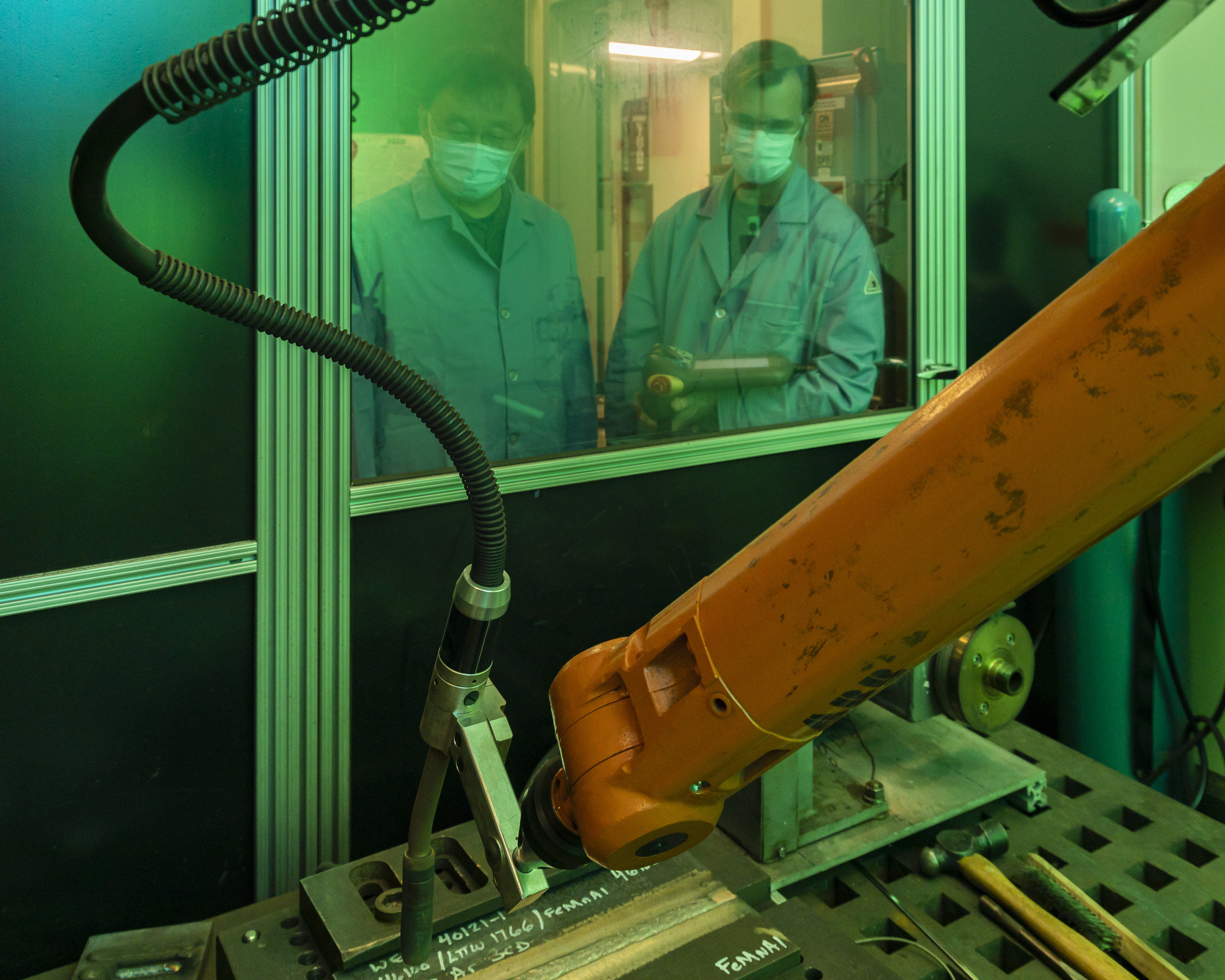 Two researchers operate a welding robot.