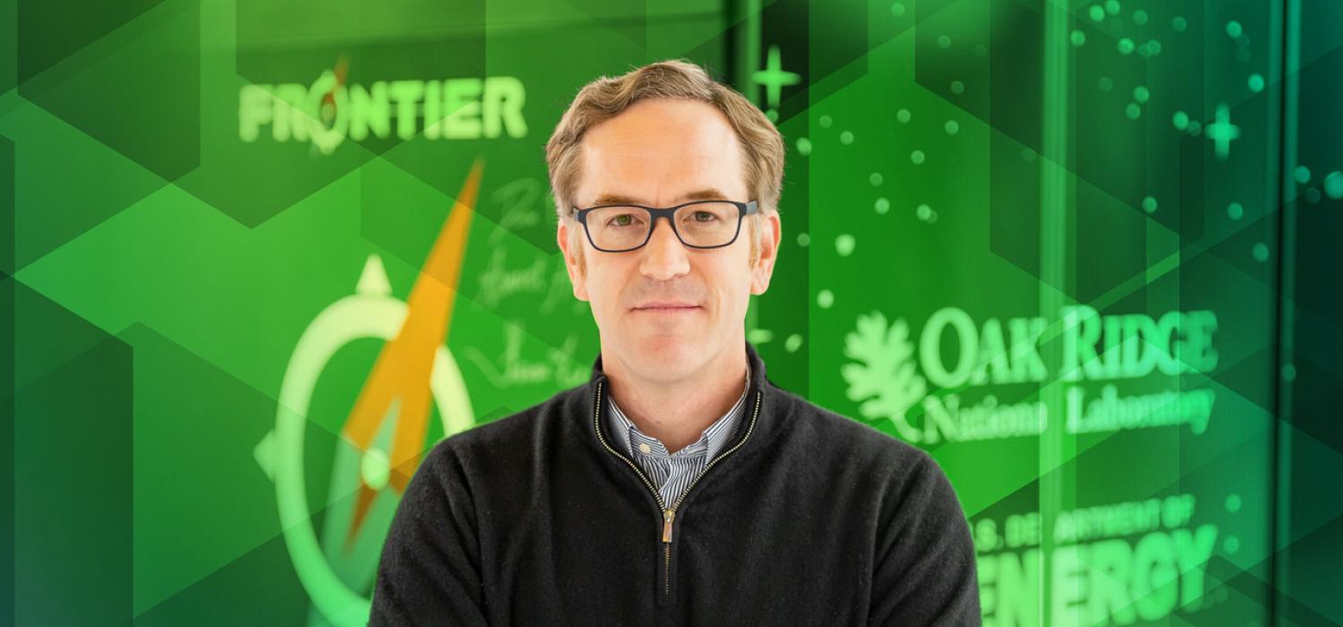Portrait of a man standing in front of Frontier supercomputer