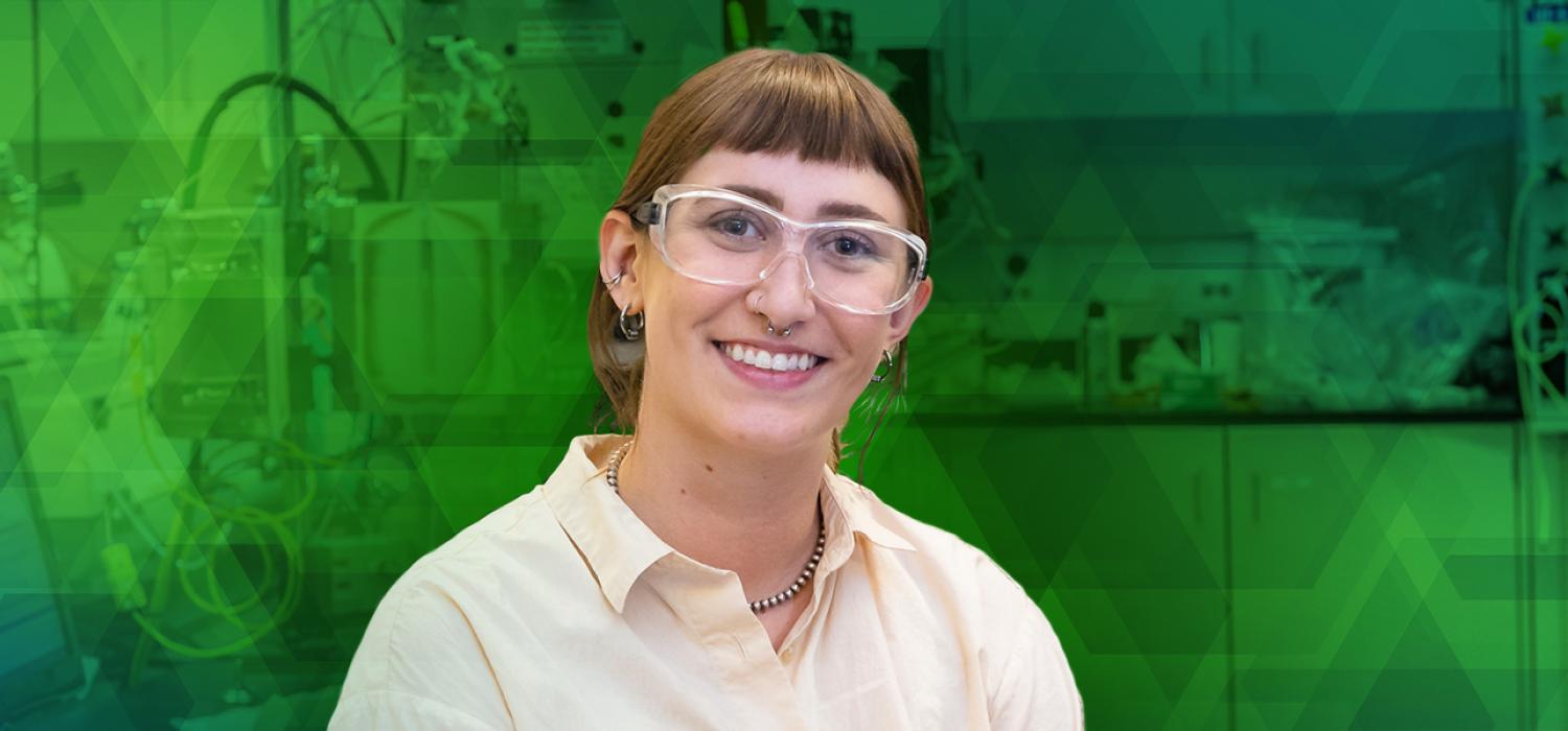 Graduate student standing in front of green hexagonal backdrop