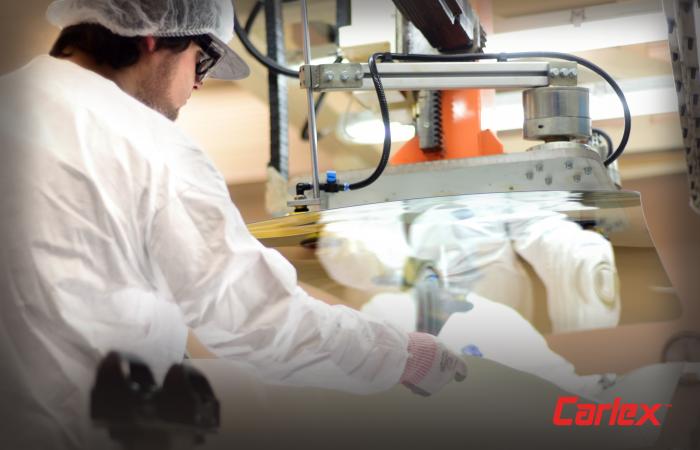 Inside the clean room, Carlex employees carefully place a PVC interlayer between two pieces of windshield glass. Credit: Carlex Glass America, LLC