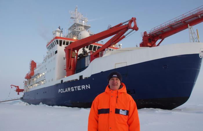 Misha Krassovski, a computer scientist at Oak Ridge National Laboratory, stands in front of the Polarstern, a 400-foot long German icebreaker. Krassovski lived aboard the Polarstern during the first leg of the MOSAiC mission, the largest polar expedition ever. Credit: Misha Krassovski/Oak Ridge National Laboratory, U.S. Dept. of Energy