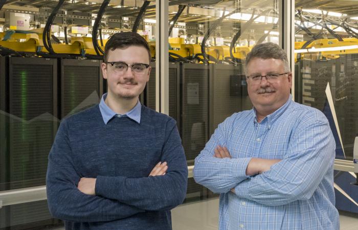 Tyler Duckworth, left, poses with his father, Robert Duckworth, in front of the Summit supercomputer.  Tyler Duckworth has been named recipient of the 2021 UT-Battelle Scholarship to attend the University of Tennessee. Credit: Carlos Jones/ORNL, U.S. Dept. of Energy