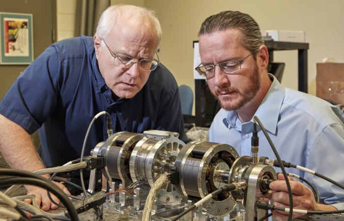 The magnetic suspension test bed shown is being used to develop control hardware, control software, and position sensing for a magnetically suspended, canned rotor water pump. L-R: Roger Kisner, Alexander Melin.
