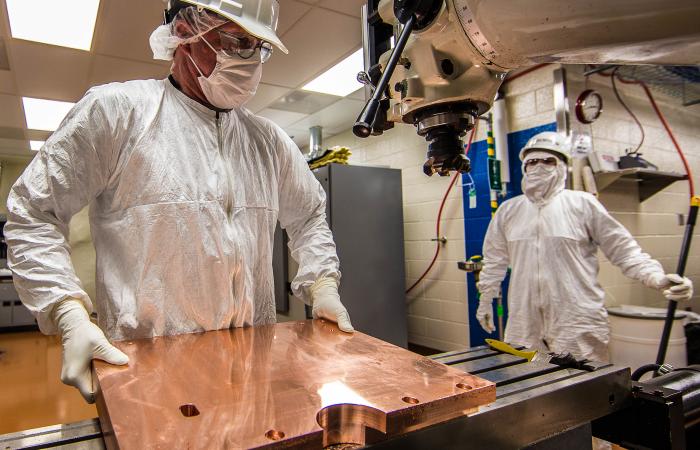 Working in a cleanroom nearly a mile underground, Randy Hughes (foreground) is the primary on-site machinist for the MAJORANA DEMONSTRATOR experiment. The innermost shield and detector components are fabricated from ultrapure copper produced by electrofor