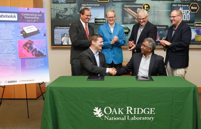 Duncan Earl, Qubitekk’s president and chief technology officer (seated, left) and Thomas Zacharia, ORNL laboratory director, participated in a signing ceremony at Oak Ridge National Laboratory with Eugene Cochran, ORNL commercialization manager.