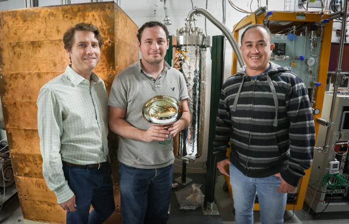 From left, Jason Newby of ORNL, Jacob Zettlemoyer of Indiana University and Hector Moreno of New Mexico State University work on the COHERENT experiment to detect neutrinos at the SNS. Shown is an 8-inch wide photomultiplier for a liquid-argon detector wi