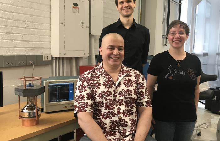 From left, Professor Juan Collar with Bjorn Scholz and Nicole Fields led detector development at the University of Chicago. A four-pound prototype detector, a replica of the 32-pound (14.5 kilogram) one used at the SNS, is at left. Fields’s 2015 Ph.D. the
