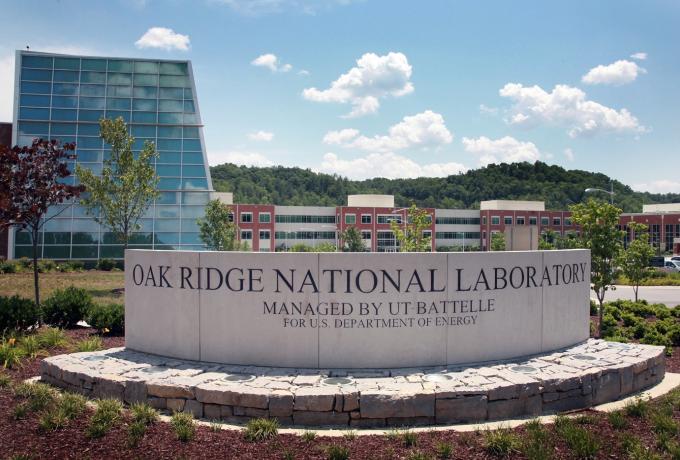 Stone entry sign that reads "Oak Ridge National Laboratory" in front of the visitor's center on a sunny day