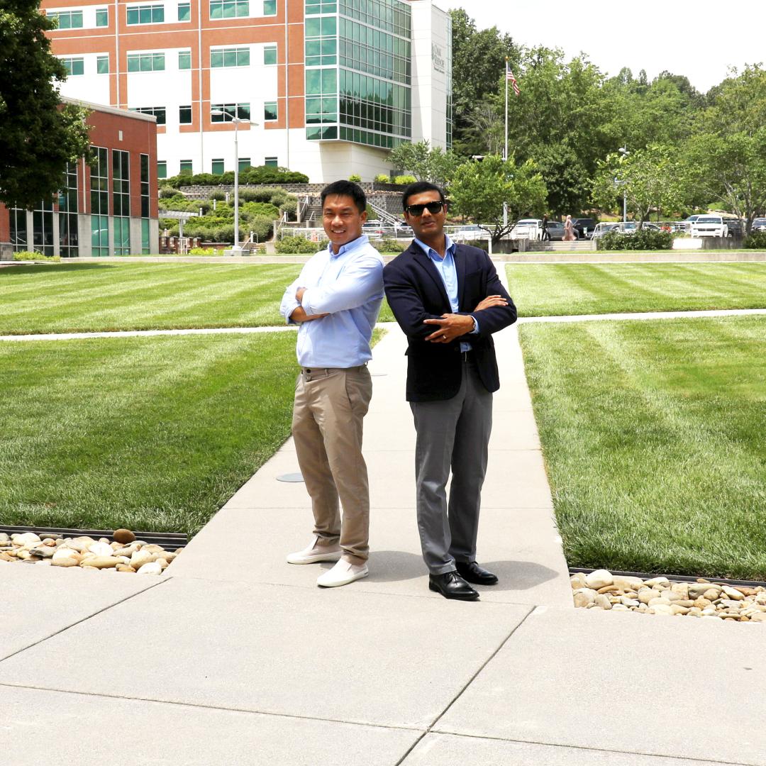 Two researchers standing back to back in a grassy area