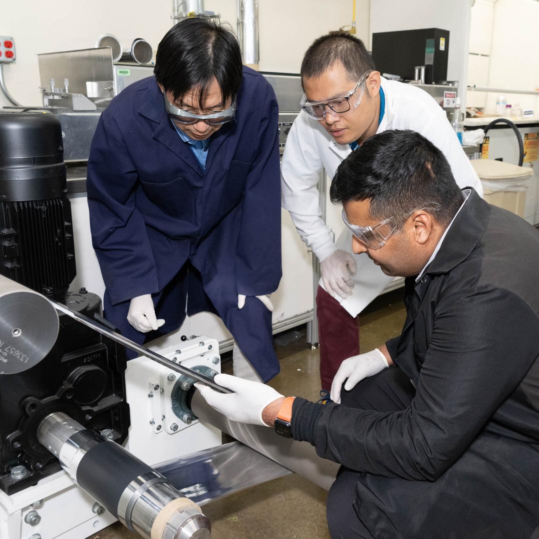 ORNL scientist Zhijia Du, white coat, former ORNL scientist Jianlin Li, blue coat, and Ateios CEO Rajan Kumar inspect battery components during a pilot production run. Credit: Kurt Weiss/ORNL, U.S. Dept of Energy