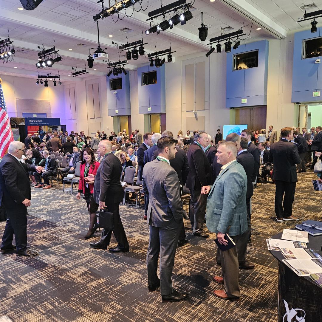 People in a large convention room networking before a presentation