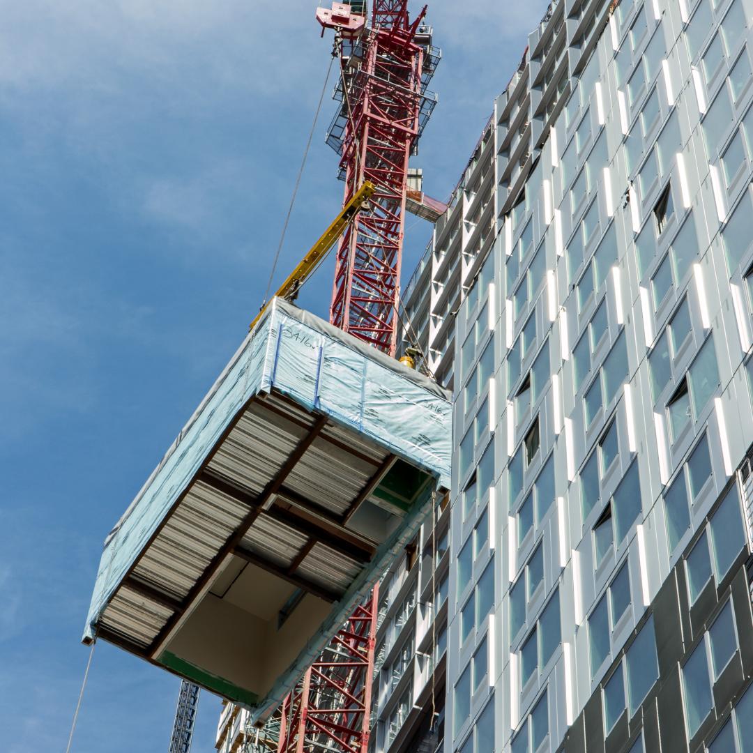 Rectangular box being lifted by a red pully system up the left side of the building