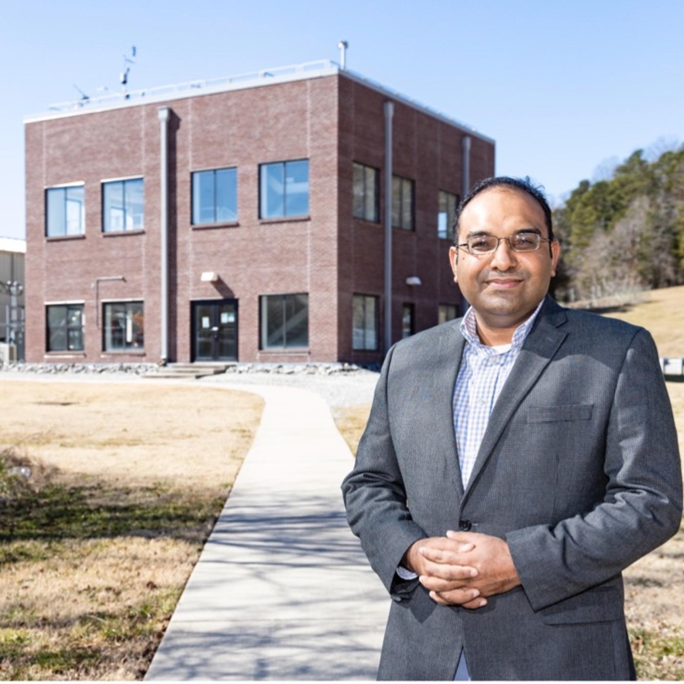 Kashif Nawaz standing in front of a two story brick building that houses active research