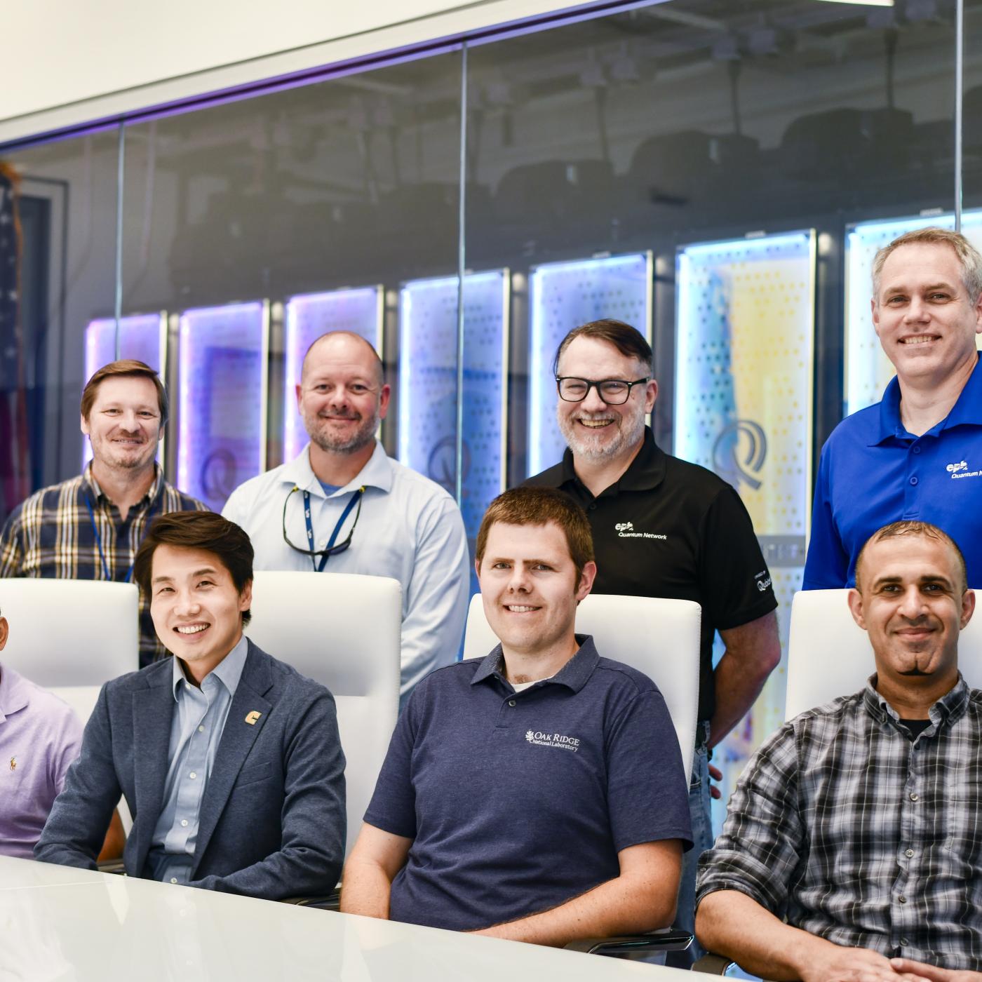 Team of four people seated in front of four people standing in the network operations center at EPB at Chattanooga.