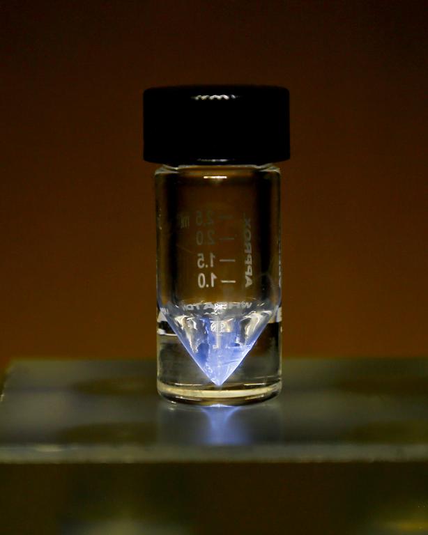 A purified sample of actinium-225, produced at ORNL’s Radiochemical Engineering Development Center, glows blue when the air that surrounds it is ionized by alpha particles. The FDA has acknowledged receipt of the Drug Master File for Ac-225 nitrate, an in-demand ingredient in targeted cancer treatments. Credit: ORNL, U.S. Dept. of Energy