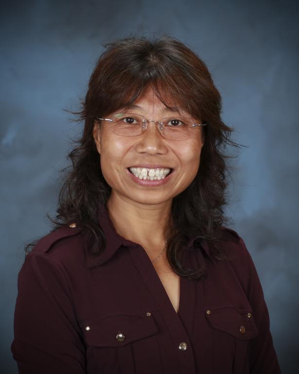 a woman with glasses wearing a maroon shirt