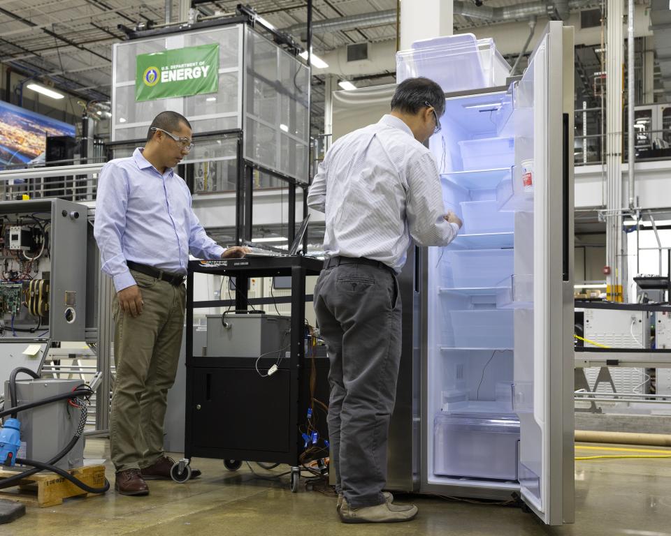 Two researchers at work with an open refrigerator in a lab