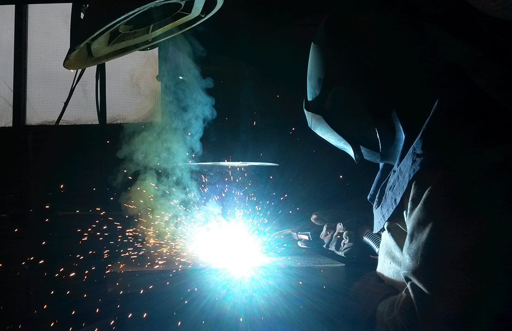 Welder with torch flare (Unsplash)