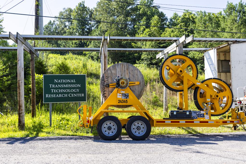 conductor line on spools to unroll from machinery next to a sign saying "National Transmission Technology Research Center"
