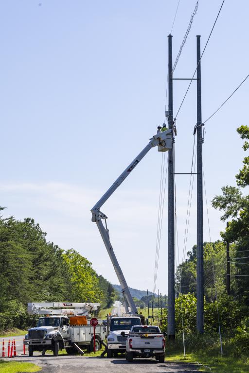 bucket trucks and utility trucks with bucket extended, next to power lines