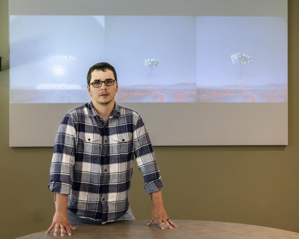 Cody Lloyd stands in front of images of historical nuclear field testing. The green and red dots are the machine learning algorithm recognizing features in the image. Credit: Carlos Jones/ORNL, U.S. Dept. of Energy
