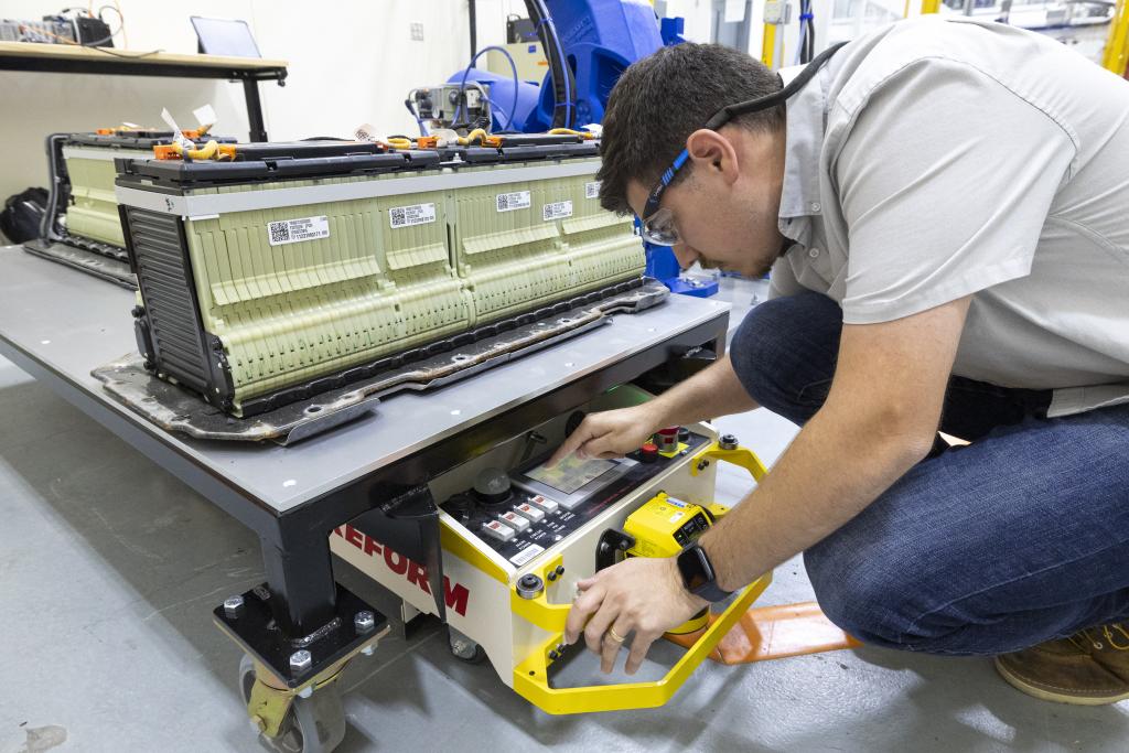 Jonathan Harter programs an autonomous guided vehicle that tows lithium-ion batteries, materials and systems around the battery recycling and reuse lab in GRID-C. Credit: Carlos Jones/ORNL, U.S. Dept. of Energy