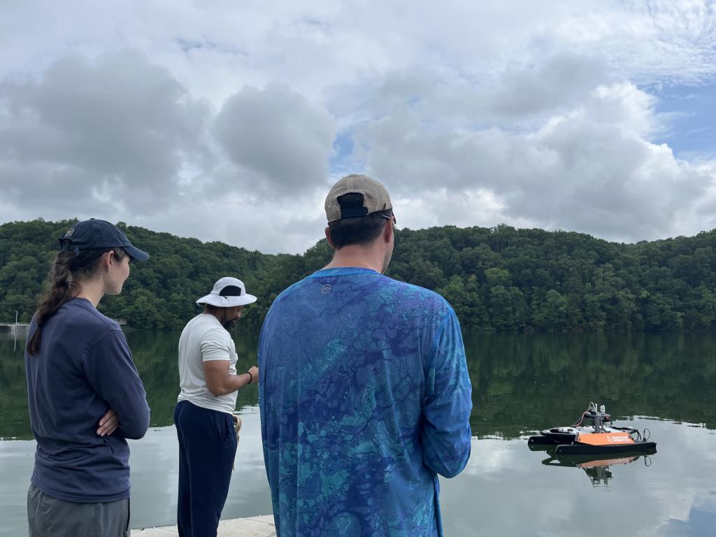 group of people pilot an aquatic drone on a river