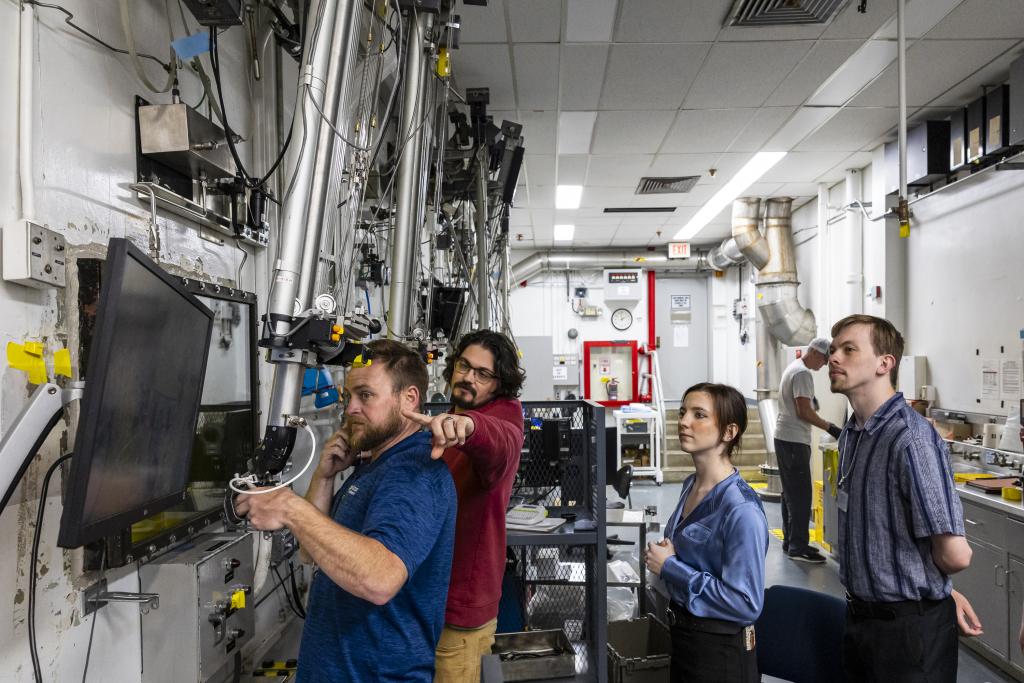 ORNL radioisotope processing technicians Ben Smiley and Aaron Saxon, left, demonstrate a manipulator used to work inside a protected hot cell in in the Radioisotope Development Laboratory, as Pellissippi State Chemical Radiation Technology Pathway students Haley Massey and Jon Rowland look on. Credit: Carlos Jones/ORNL, U.S. Dept. of Energy