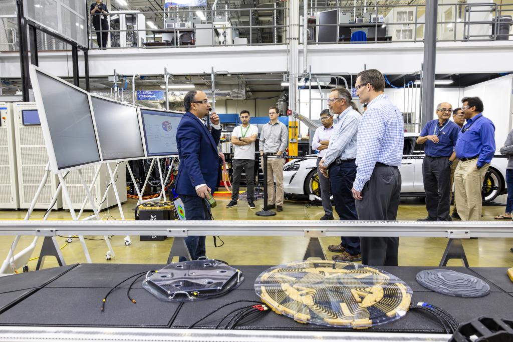 ORNL's Omer Onar, left, power electronics research lead, discusses the 270-kW wireless charging system's lightweight polyphase electromagnetic coupling coil, pictured in foreground