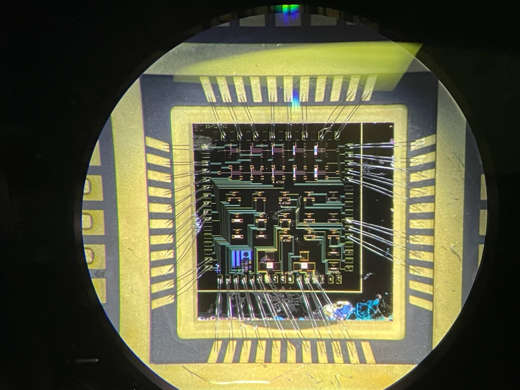 A wire-bonded die consisting of over 20 gallium nitride high-electron mobility transistors, seen here under a microscope