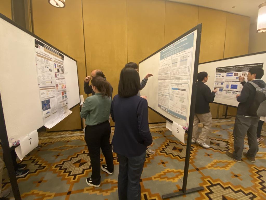 Three attendees are looking at poster sessions