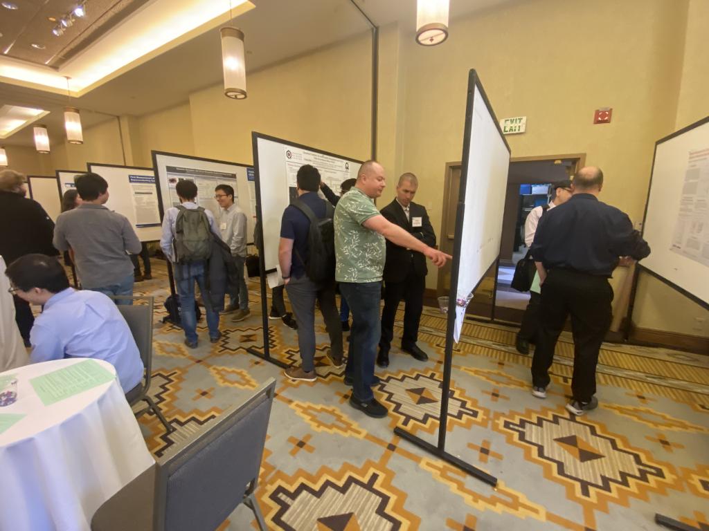 Multiple groups of people are looking at poster presentations