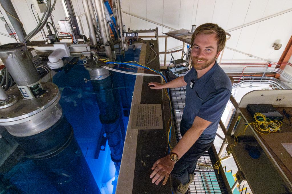 Man in a blue polo is standing over blue water 