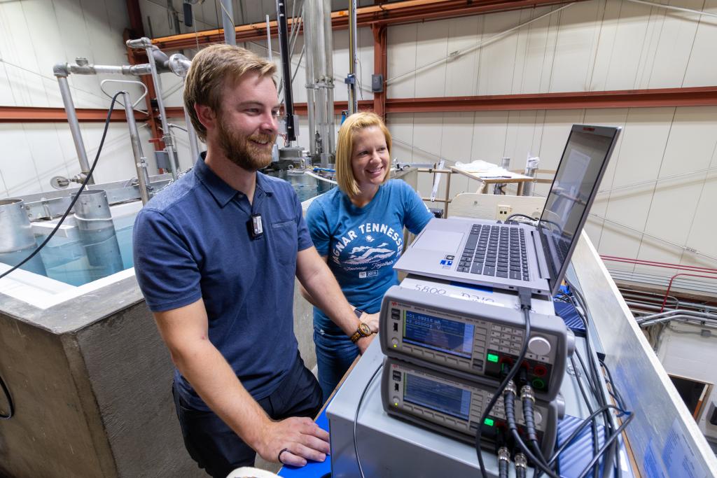 A man and a woman are looking at a computer, both dressed in blue