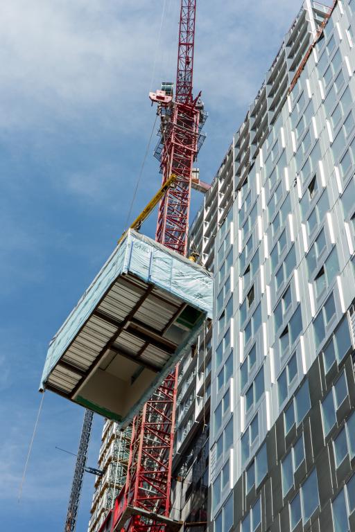 Rectangular box being lifted by a red pully system up the left side of the building