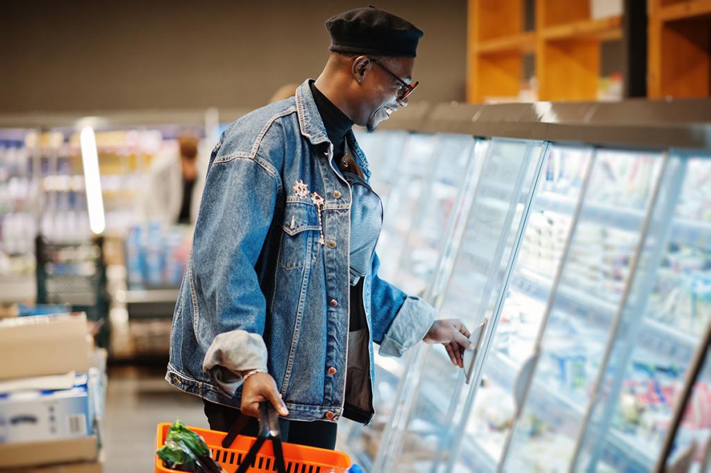 Man grocery shopping opens a refrigerated case.