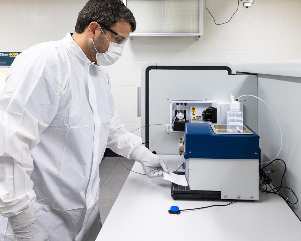 Benjamin Manard standing in front of mass spectrometer on counter top.