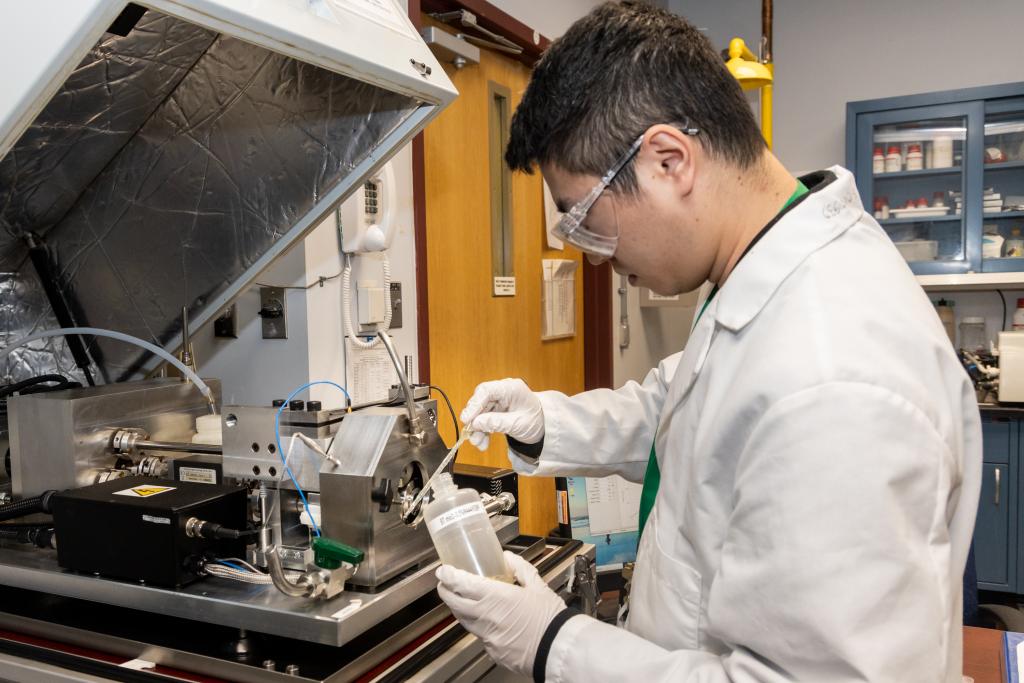 A researcher applies a lubricant to test pieces to evaluate its performance.