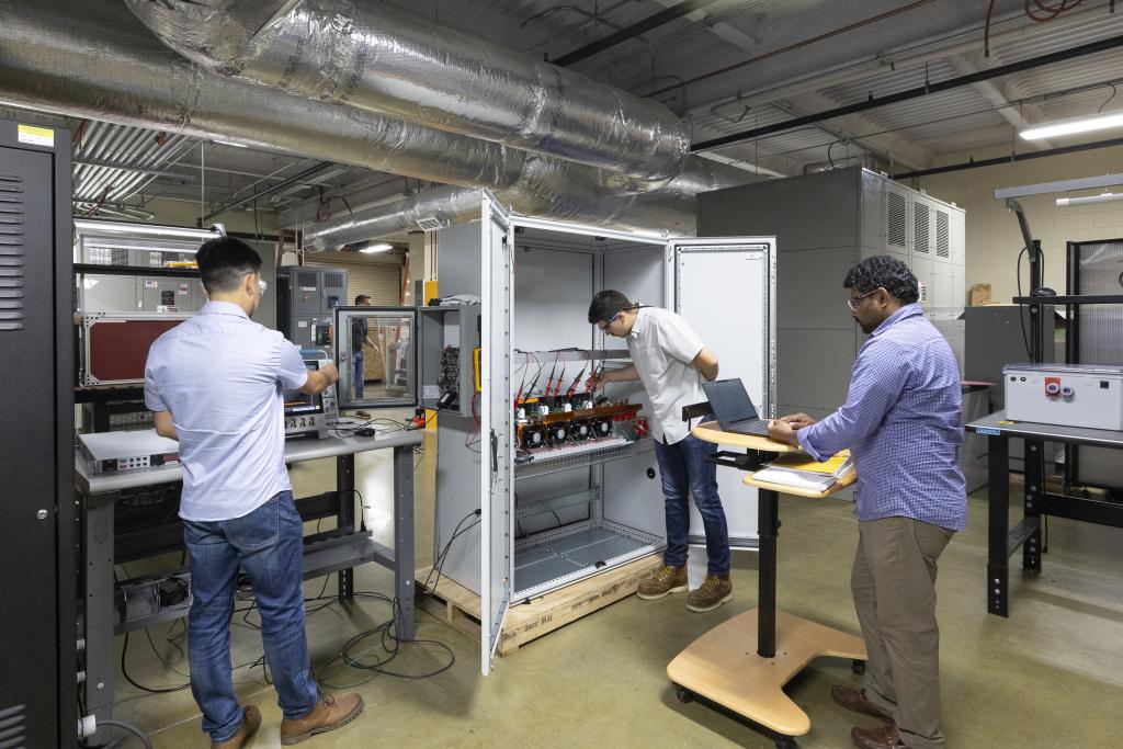 Three scientists in a lab testing electrical equipment