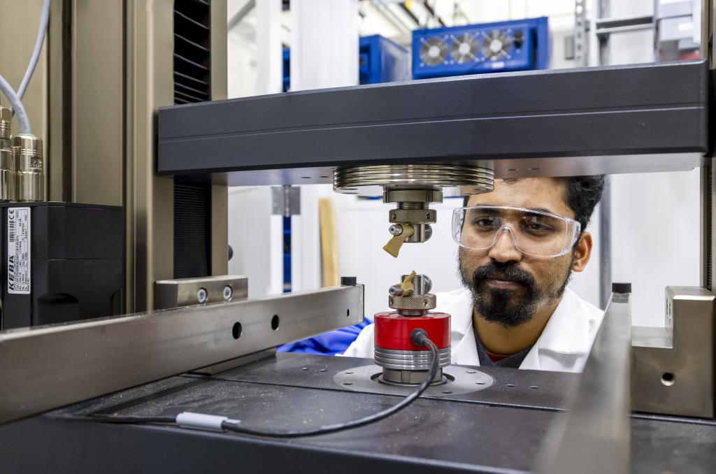 Man in safety glasses peering at battery inside test chamber