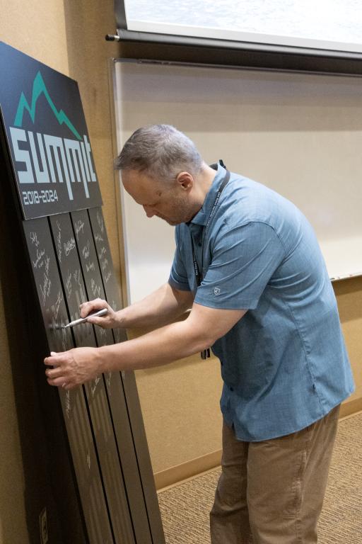 Bronson Messer, OLCF director of science, signs a piece of a cabinet door from the Summit supercomputer during the OLCF User Meeting on Sept. 11, 2024. Credit: Carol Morgan/ORNL, U.S. Dept. of Energy