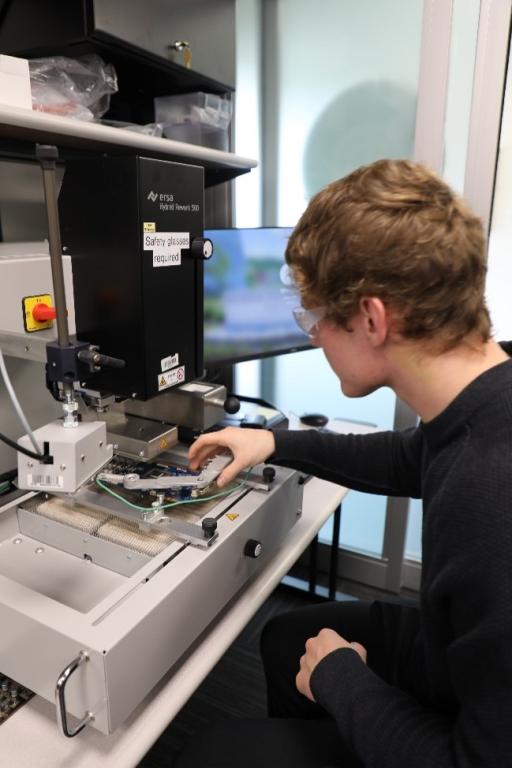 Colin Tarkington examines a circuit board. Credit: Josie Fellers/U.S. Dept. of Energy