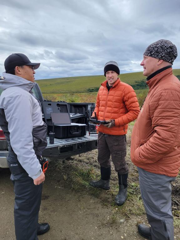 Daryl Yang standing outside at the bed of a truck with ORNL's Geoff Schwaner and Misha Krassovski 