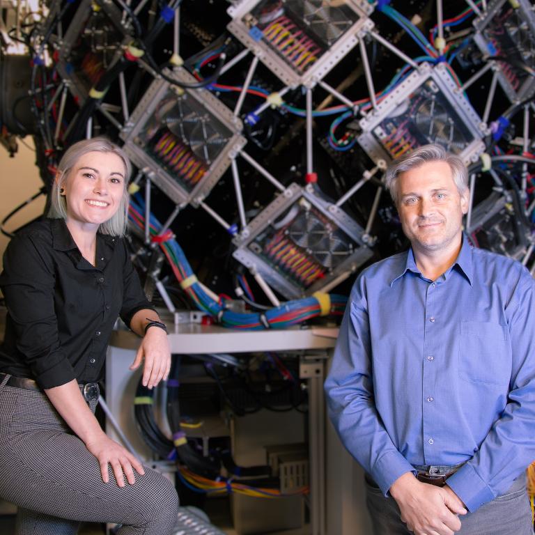 Victoria and Andrii posing in front of a large instrument at the Spallation Neutron Source.