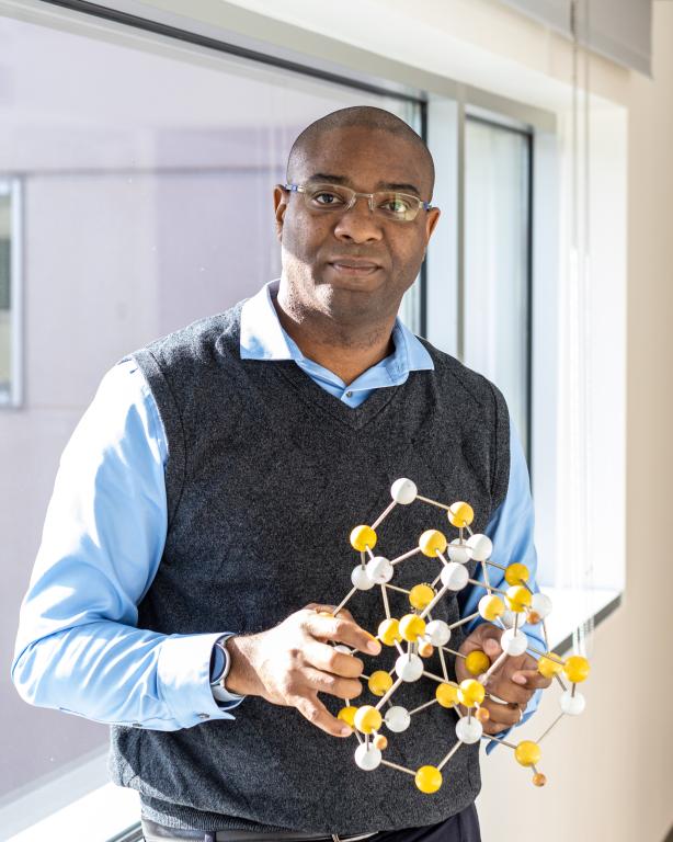 Valentino Cooper is standing holding a diagram of an atom