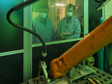 Oak Ridge National Laboratory materials scientist Zhili Feng, left, looks on as senior technician Doug Kyle operates a welding robot inside a robotic welding cell. Credit: Carlos Jones/ORNL, U.S. Dept. of Energy